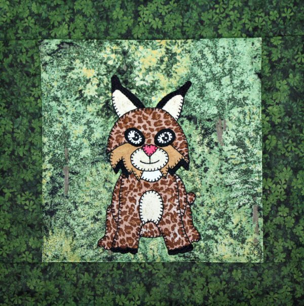 A Bobcat applique on a green background.