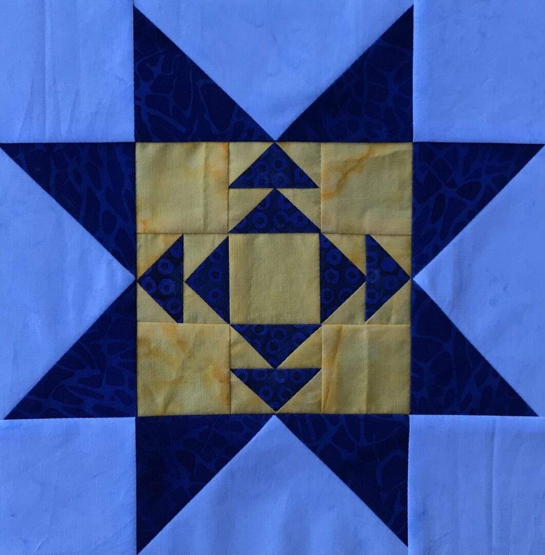 A blue and yellow Campfire Star quilt block with a star in the middle.