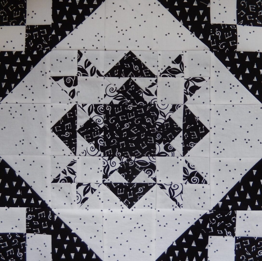 A black and white quilt block with a Christmas Star Variation in the middle.