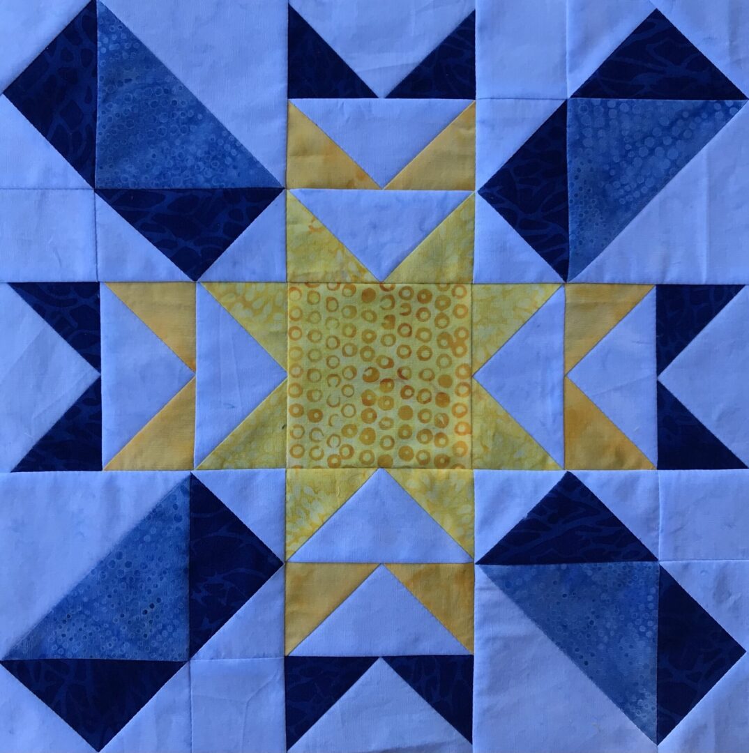 A blue and yellow Circling Overhead quilt block with a star in the middle.