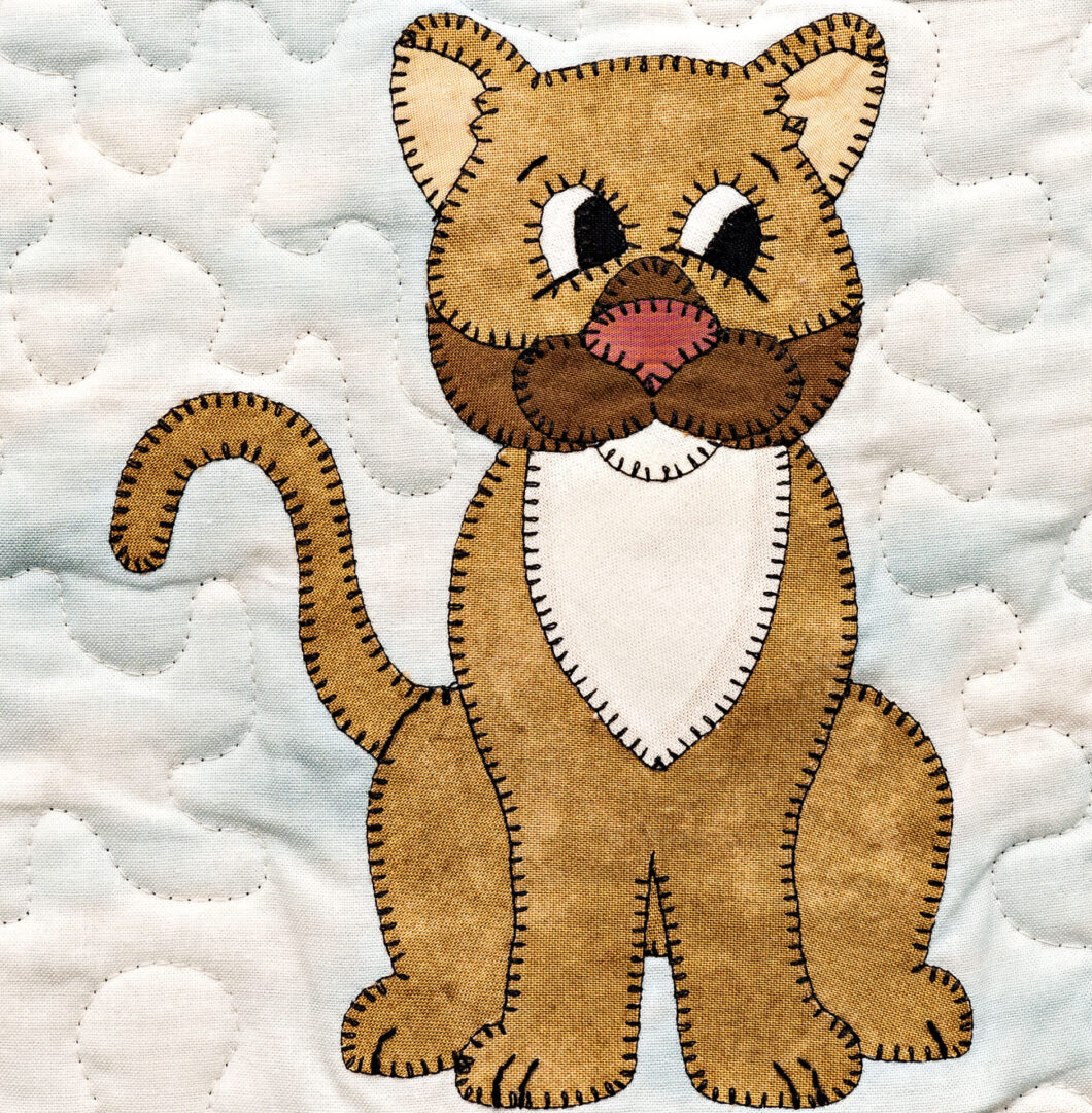 A brown cougar is embroidered on a quilt.