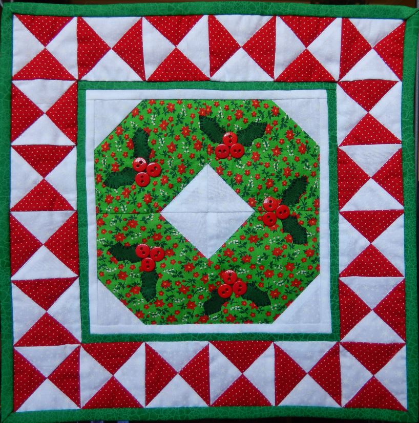 A wreath mini quilt with green and red berries.