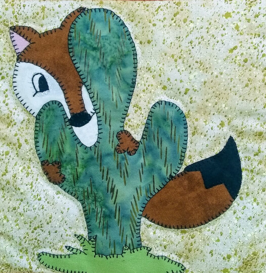 A Desert Fox with a cactus on a piece of fabric.