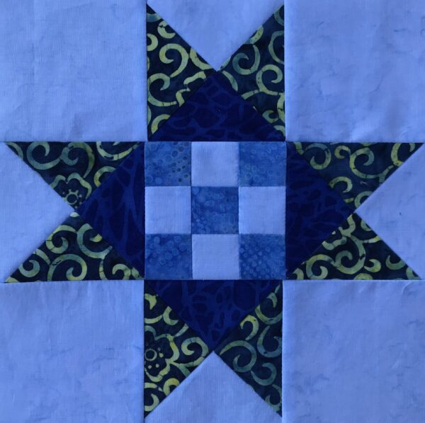 A blue and green Dolly Madison Star quilt block with a star in the middle.