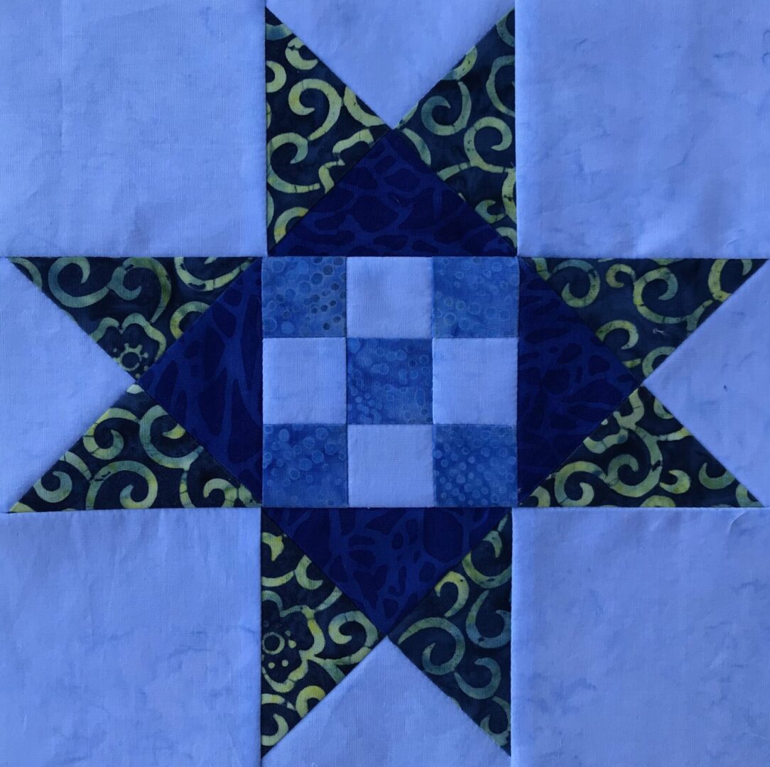 A blue and green Dolly Madison Star quilt block with a star in the middle.