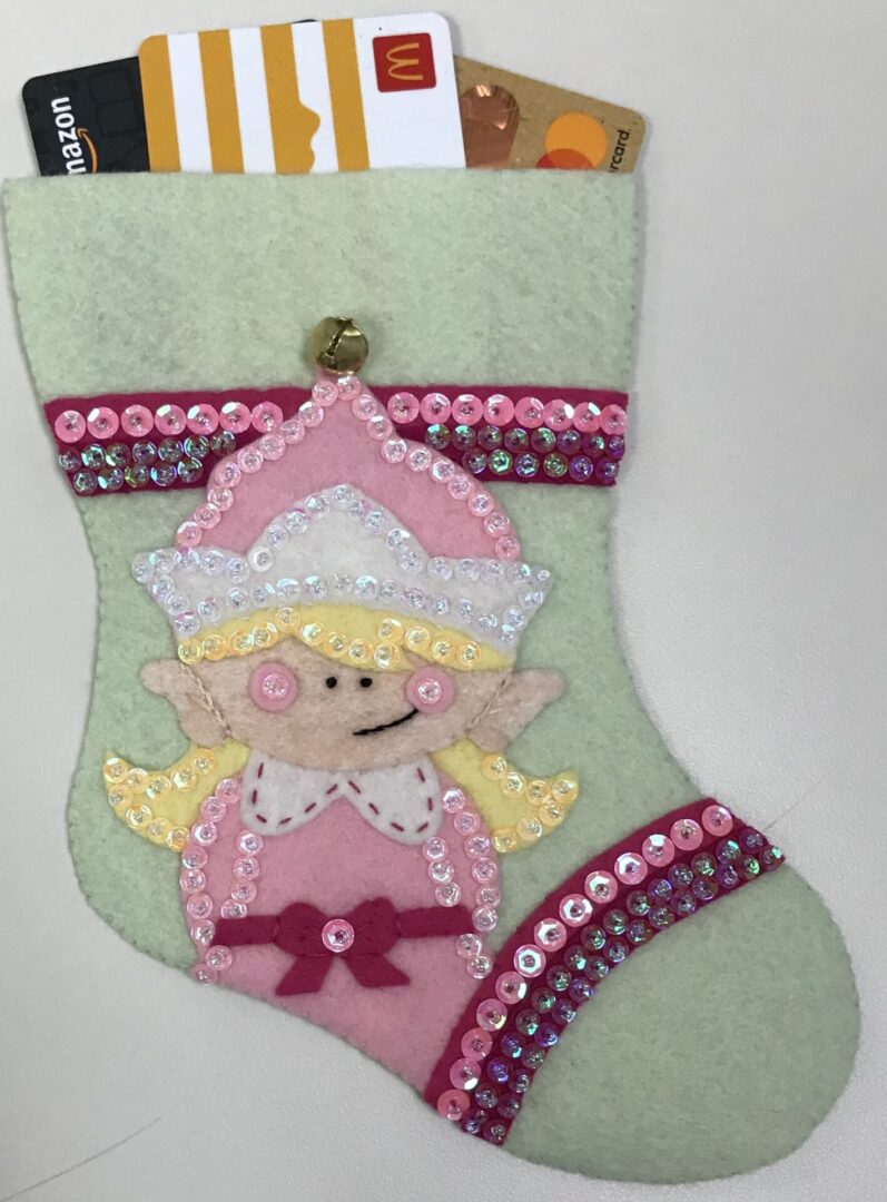 A felt stocking with the Elf Girl Gift Card Holder attached to it.