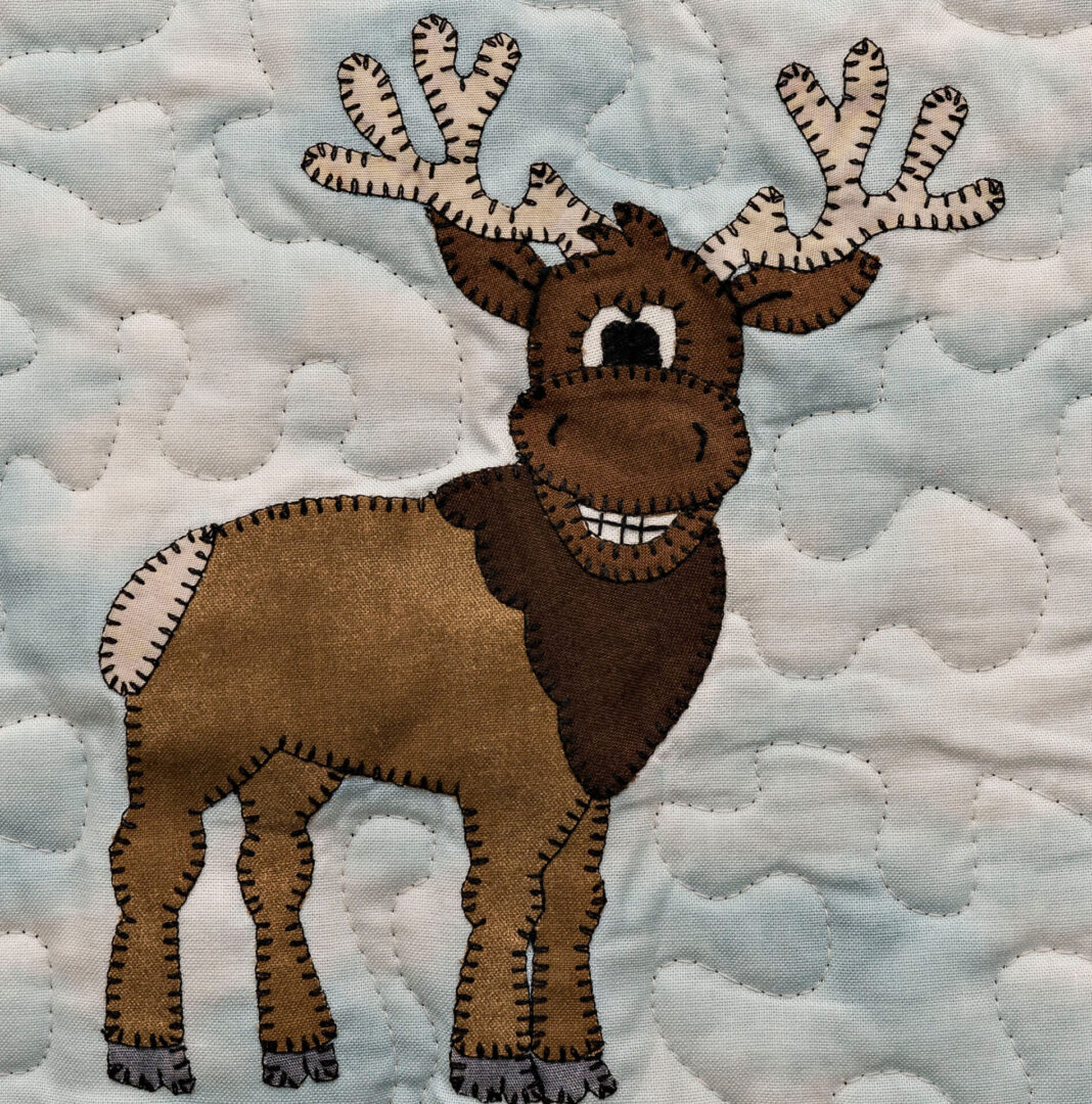 A brown Elk with antlers on a blue quilt.