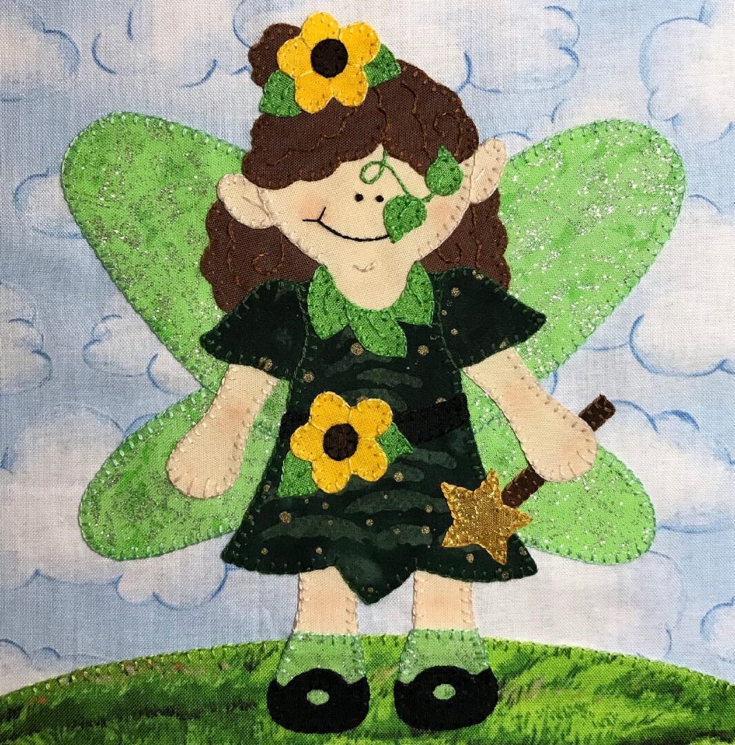 A green Fairy Tale - Faery appliqued on a piece of fabric.