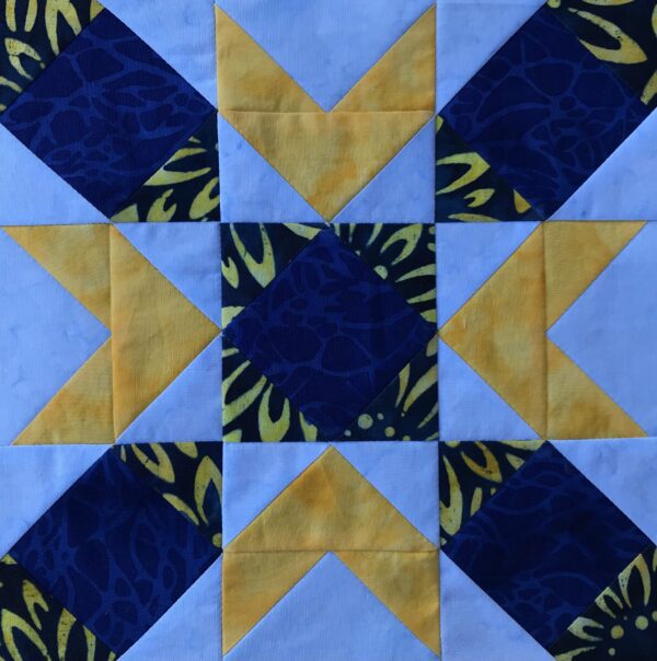 A blue and yellow quilt block with a star in the middle called Glad Tidings.