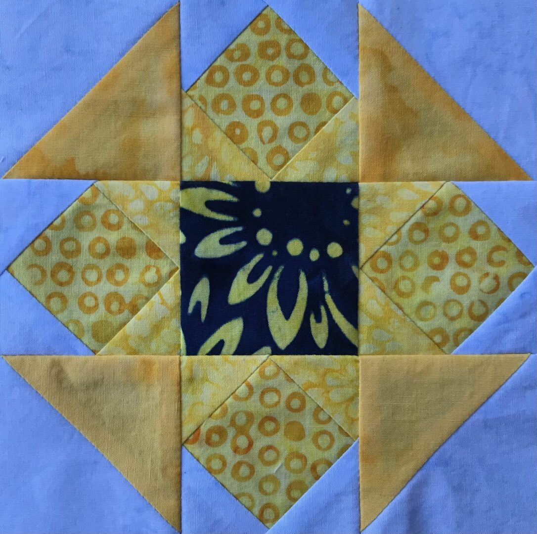 A Hidden Star quilt block with a yellow and blue design.