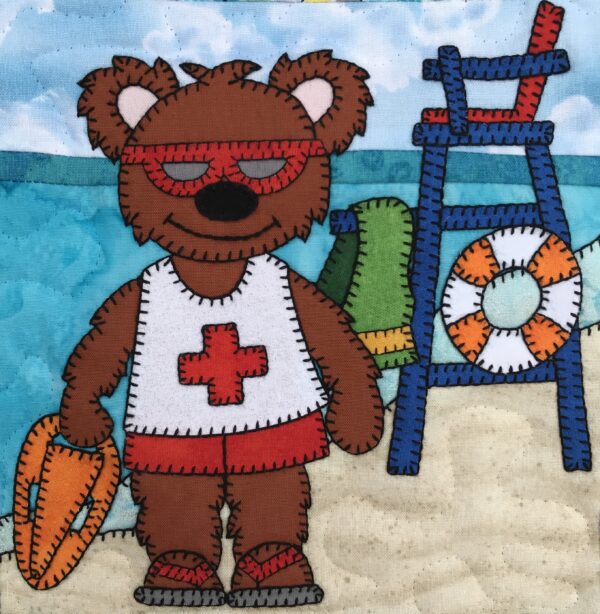 A Lifeguard Bear with a life jacket on the beach.