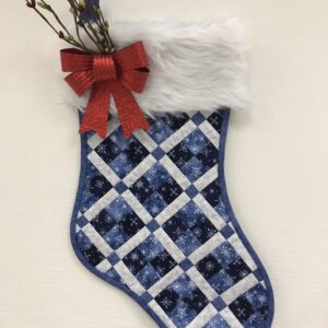 A Ms. P's Pieced Christmas Stocking with a bow.