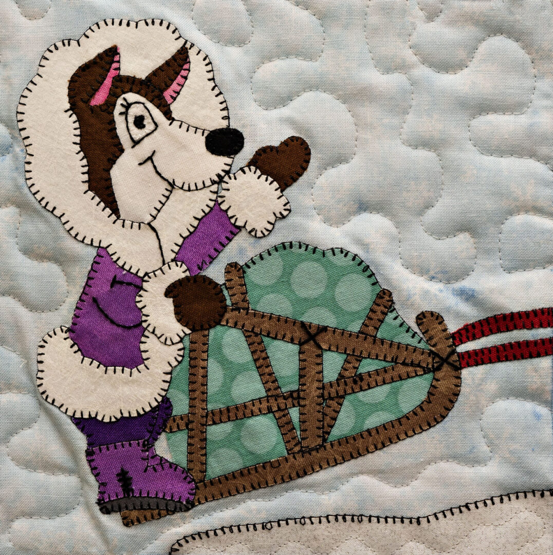 A quilt with a Husky - Musher on a sled.