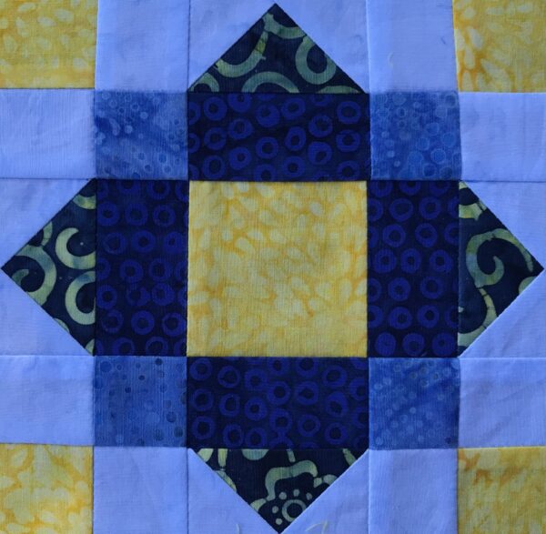 A blue and yellow Nine Patch Square quilt block with a square in the middle.