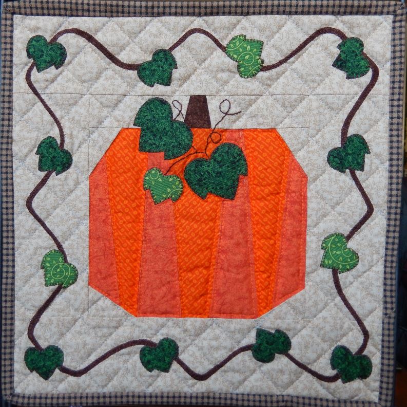 A Pumpkin Mini Quilt hanging on a wall.