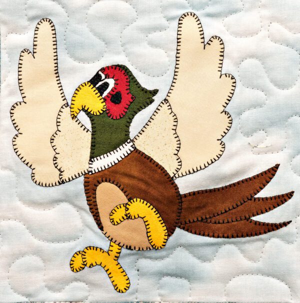 A Pheasant flying on a quilt.