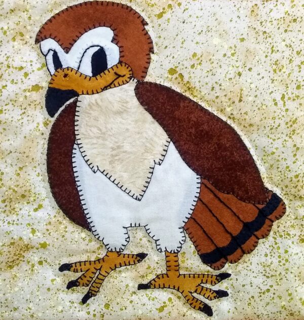 A brown and white Hawk is embroidered on a piece of fabric.