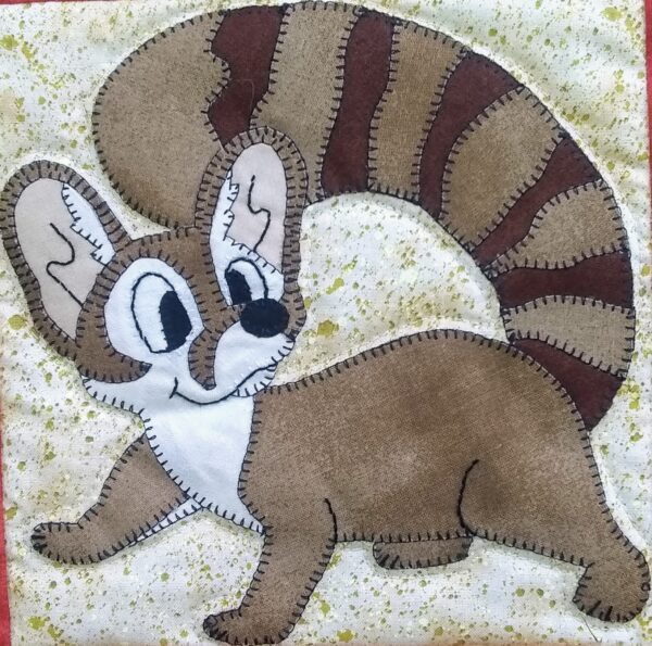 A brown and white Ring-tailed Cat is embroidered on a wall.