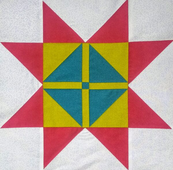 A quilt block with a Shoo Fly Star on a grey background