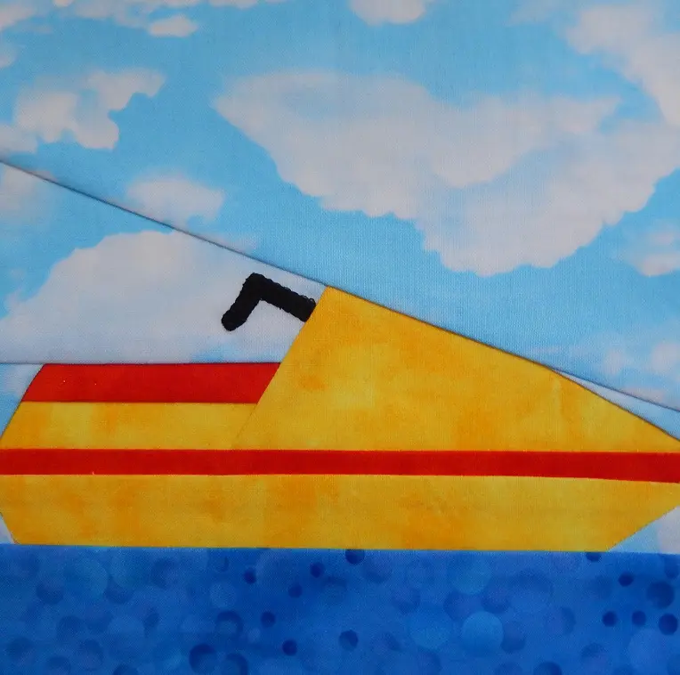 A quilt block with a yellow Personal Watercraft on the water.