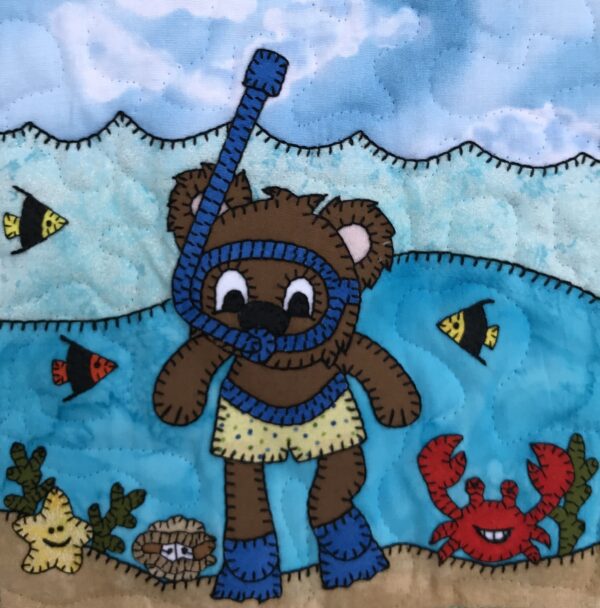 A Snorkel Bear with crabs on a quilt.