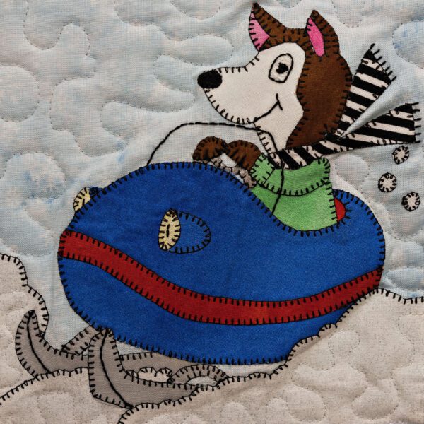 A Husky - Snowmobile is riding a sled on a quilt.