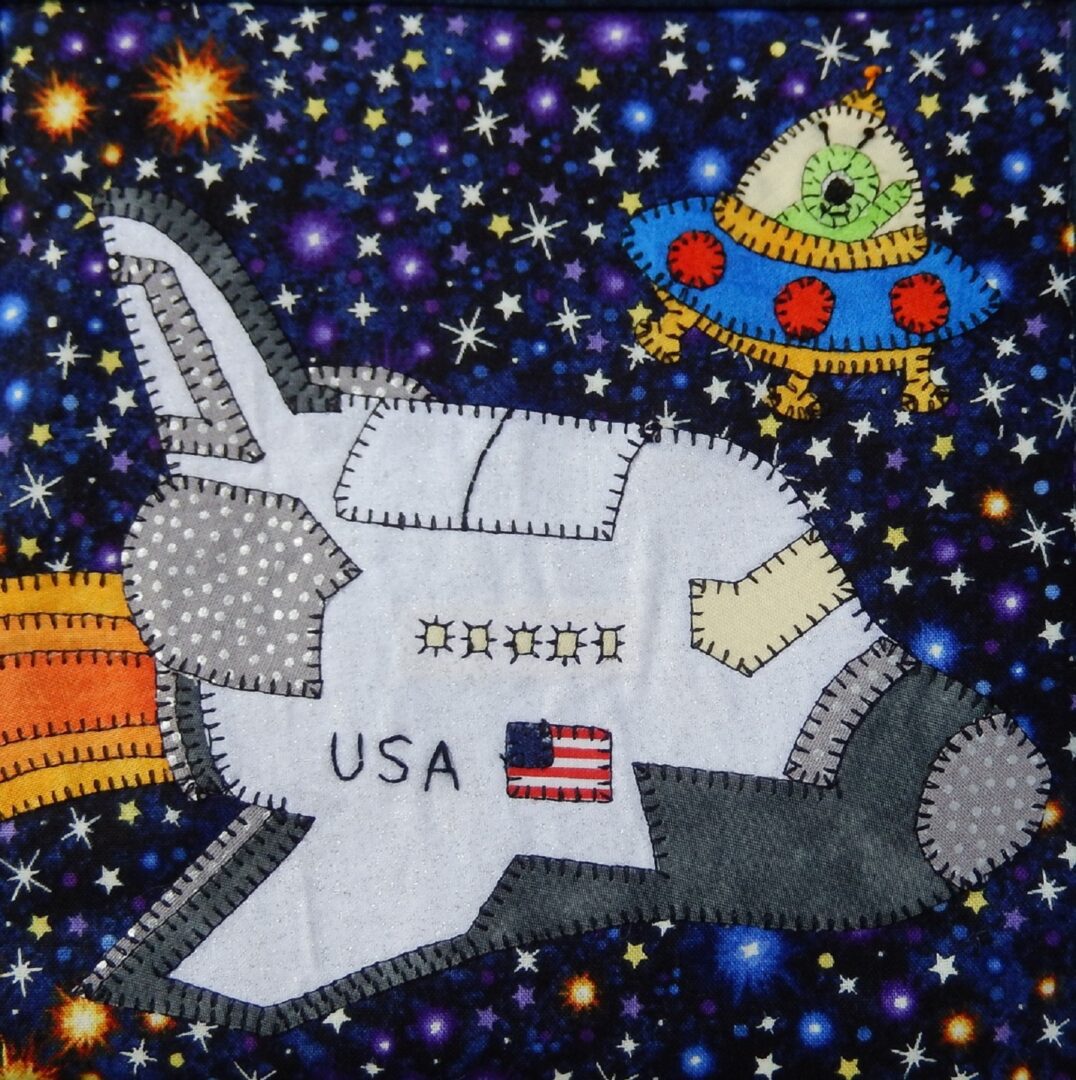 A patchwork quilt with the Space Race - Space Shuttle in the background.