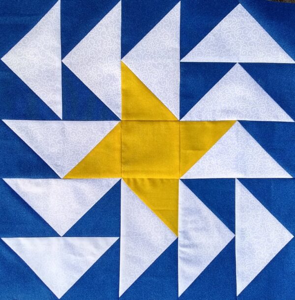 A blue and yellow quilt block with a Starlight Geese.