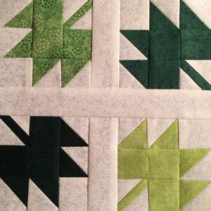 A Tumbling Leaves quilt block with green and white leaves.