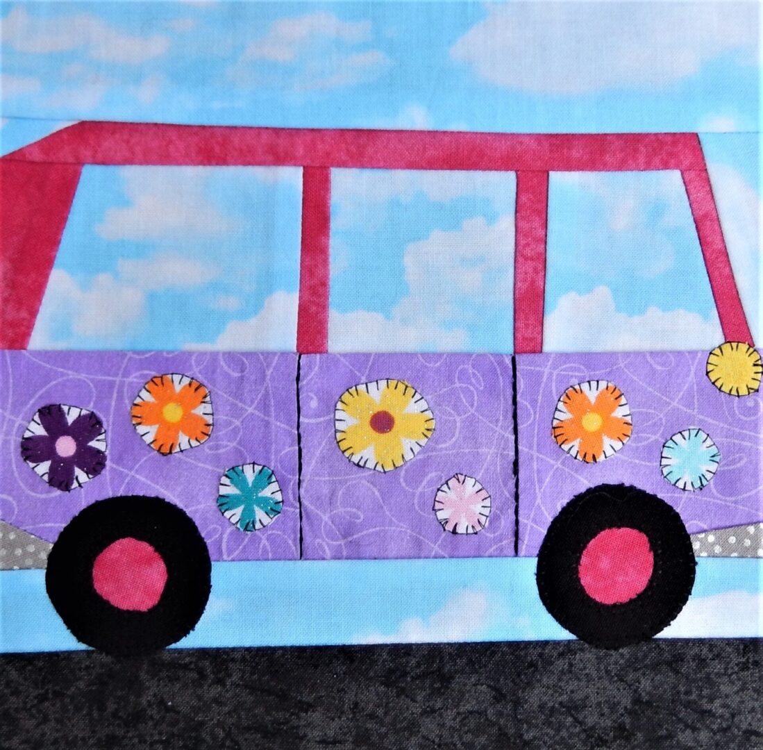 A quilt block with a purple VW Bus with flowers on it.