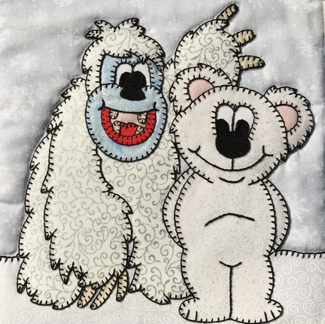 A white yeti bear and a teddy bear appliqued on a piece of fabric.