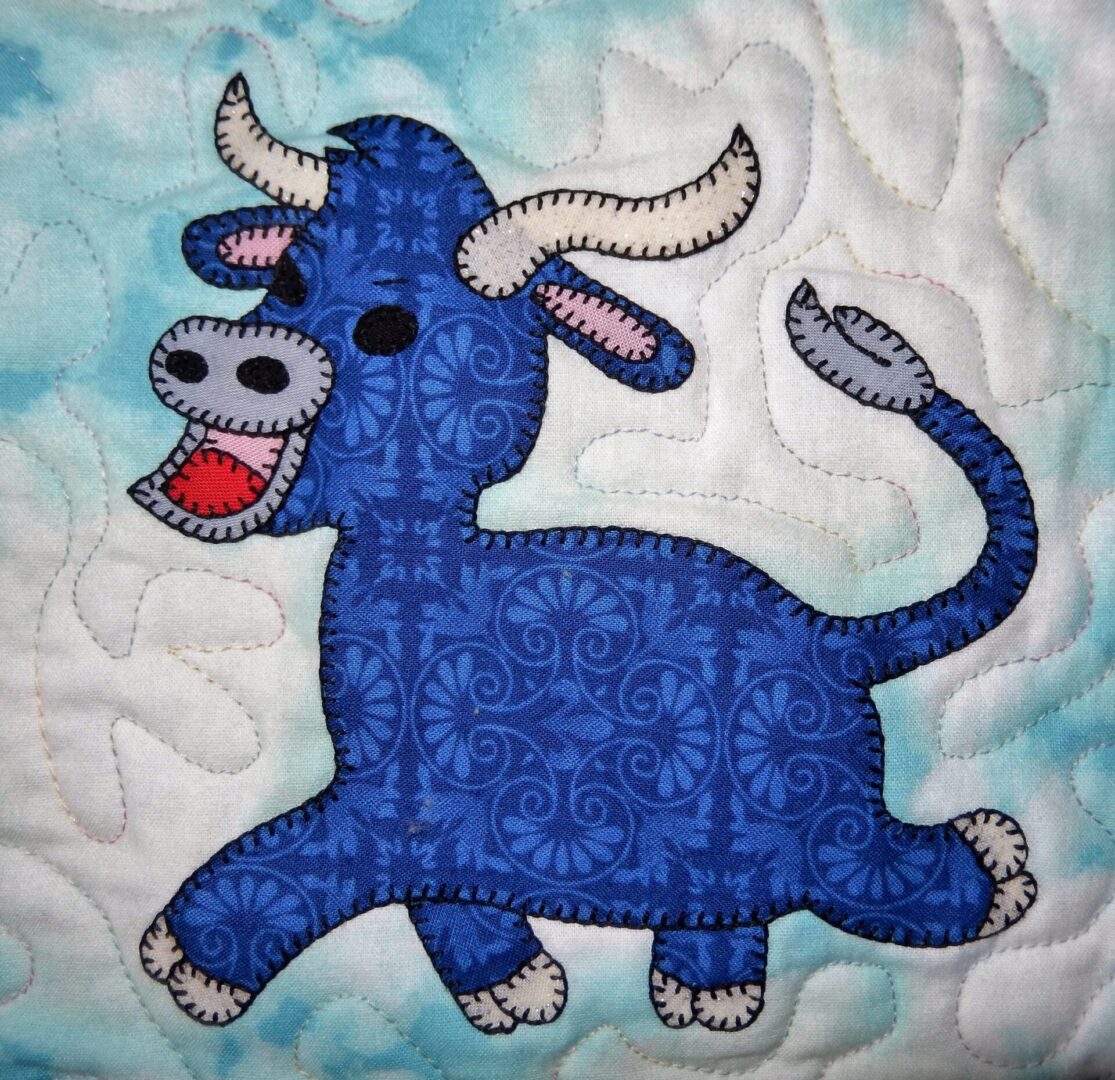 A blue quilted wall hanging with a Bull on it.