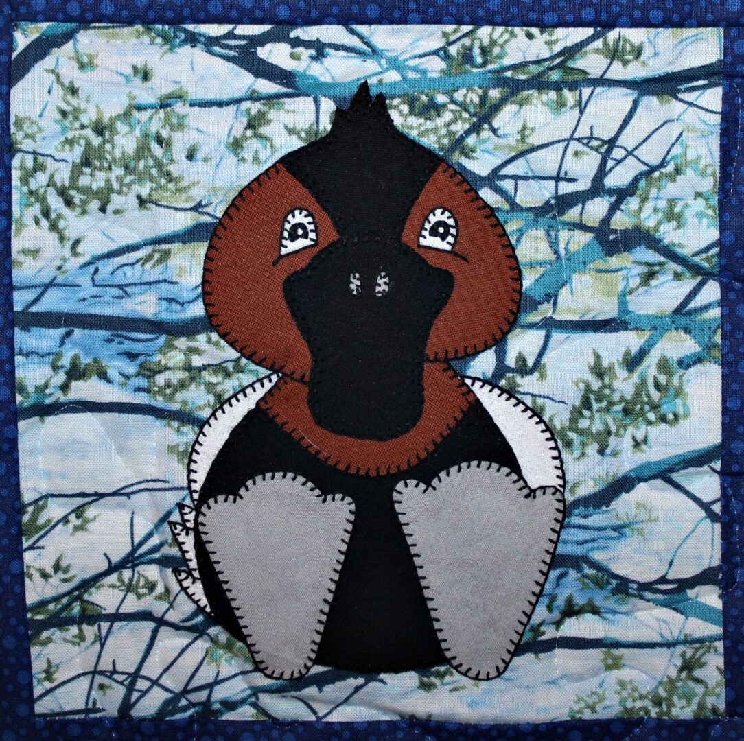 A quilt with a black and brown Canvasback Duck on it.