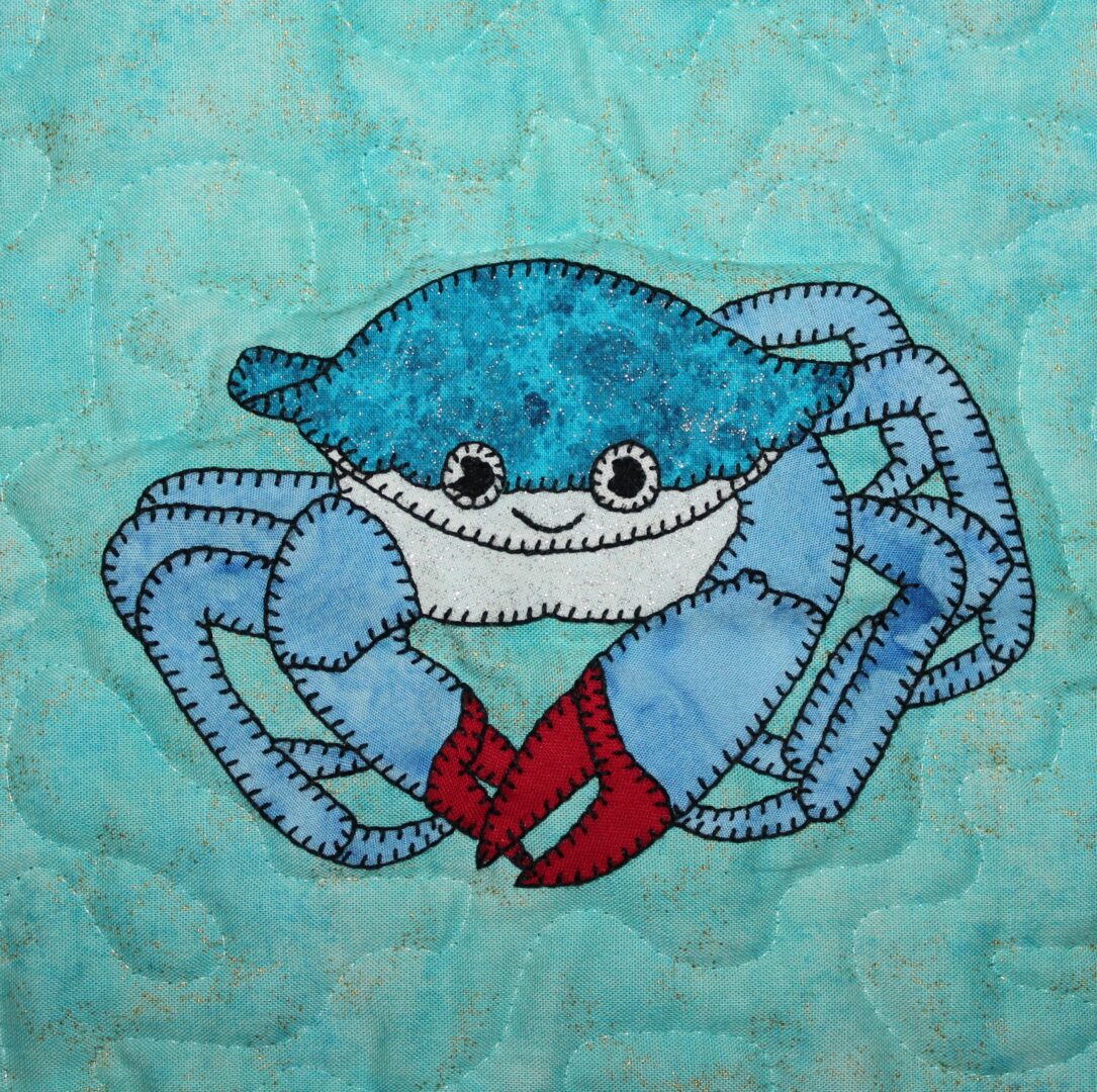 A Crab is embroidered on a blue background.