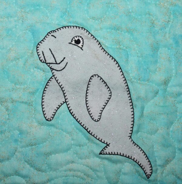 A dugong is appliqued on a blue quilt.