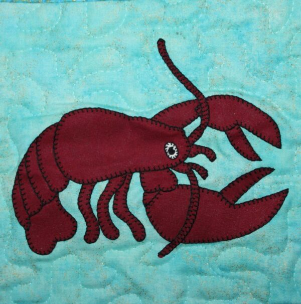 A Lobster appliqued on a blue quilt.