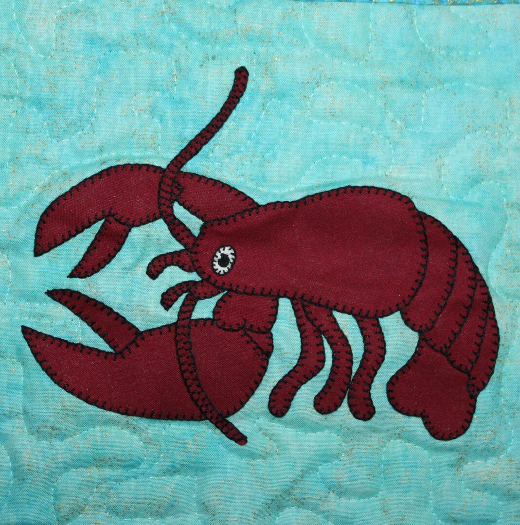 A Lobster appliqued on a blue quilt.