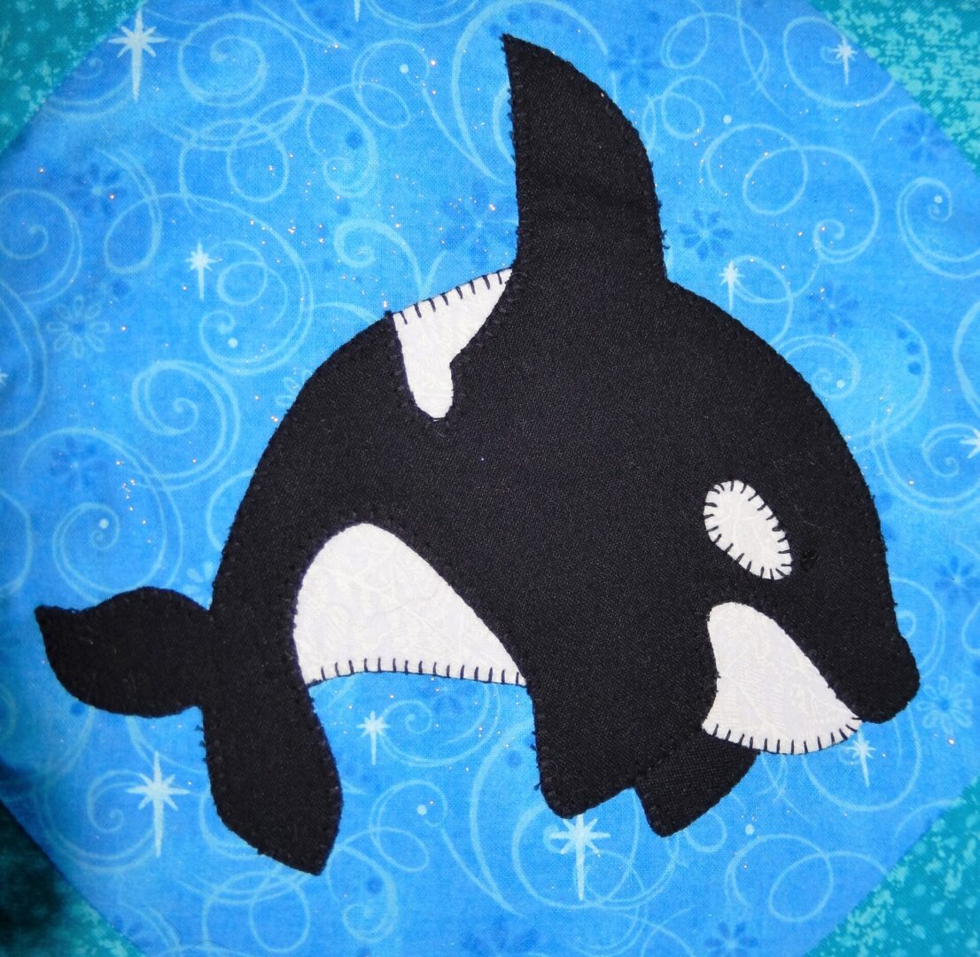 An Orca whale is embroidered on a blue square.