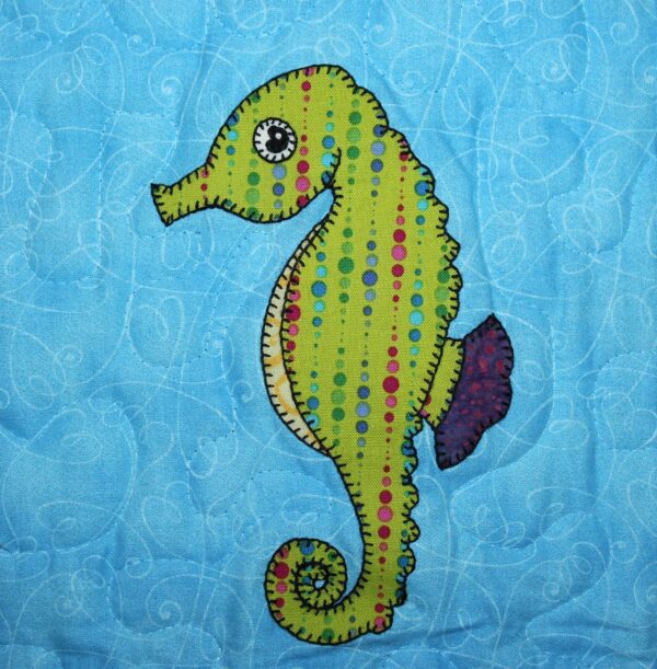 A Seahorse is appliqued on a blue quilt.