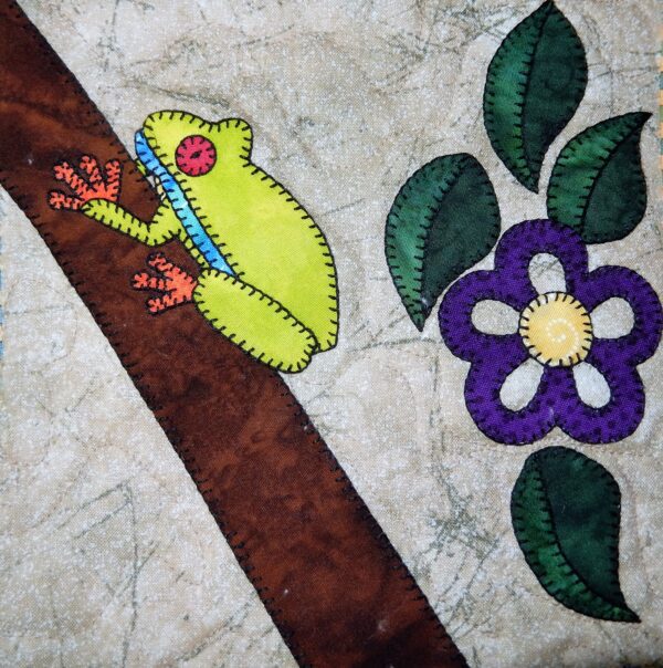 A Tree Frog quilt with a frog and flower on it.